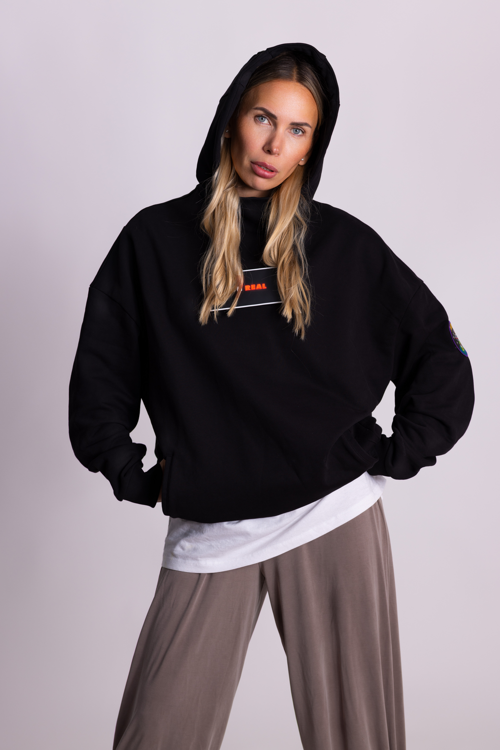 Person, die einen schwarzen Falkenstern-Hoodie mit Falkenmotiv auf dem Rücken vor einem einfarbigen Hintergrund trägt