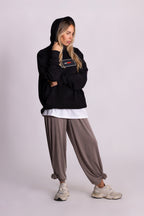 Person, die einen schwarzen Falkenstern-Hoodie mit Falkenmotiv auf dem Rücken vor einem einfarbigen Hintergrund trägt