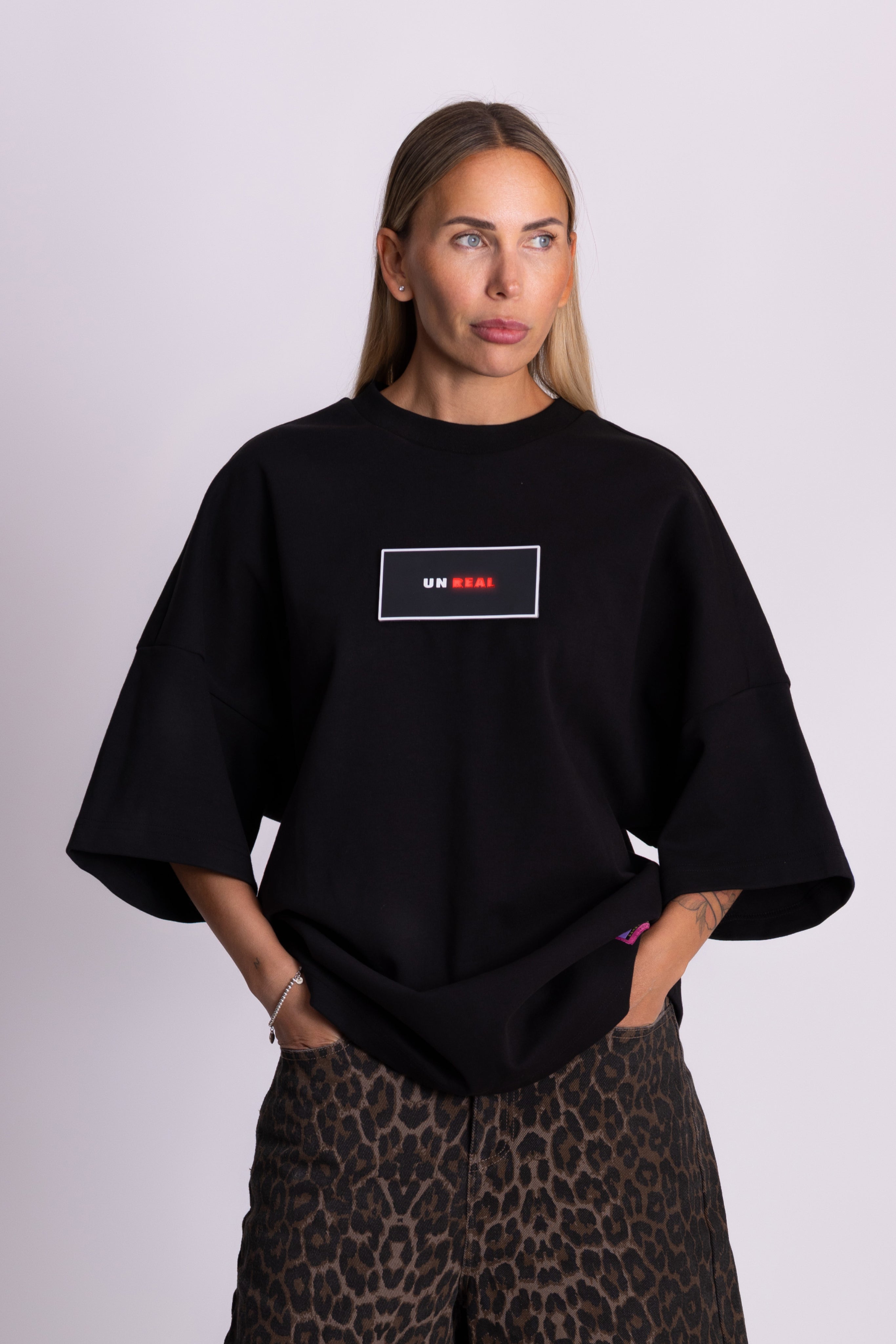 Person trägt ein schwarzes Falkenstern Damen-T-Shirt mit Falkenmotiv auf dem Rücken vor einfarbigem Hintergrund