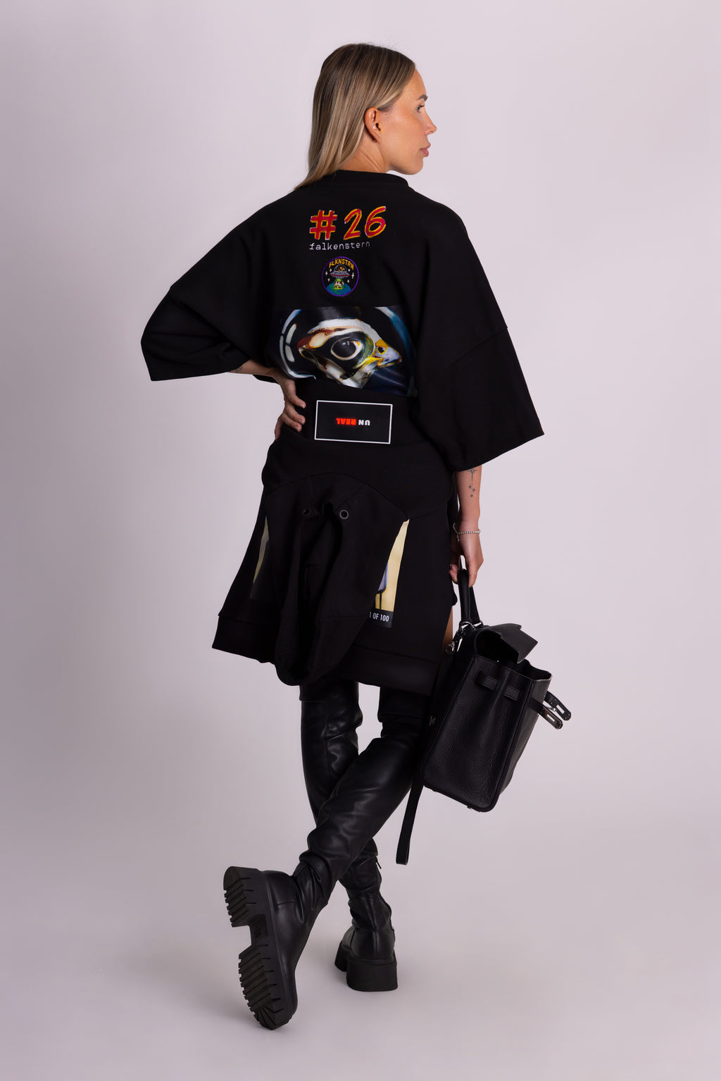 Person, die ein schwarzes Falkenstern-T-Shirt mit Falkenmotiv auf dem Rücken vor einem einfarbigen Hintergrund trägt