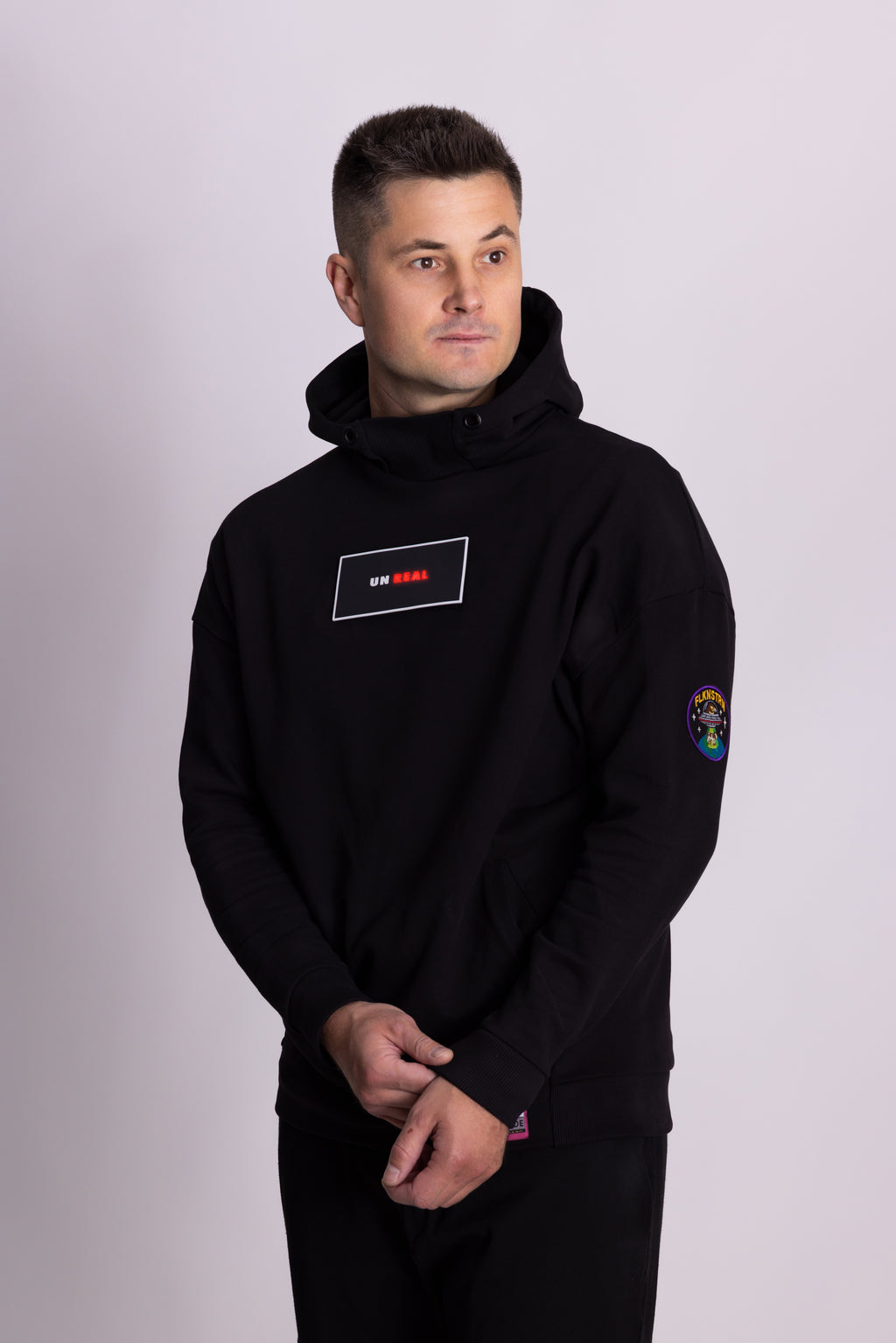 Mann mit schwarzem Kapuzenpullover mit Logos auf hellgrauem Hintergrund