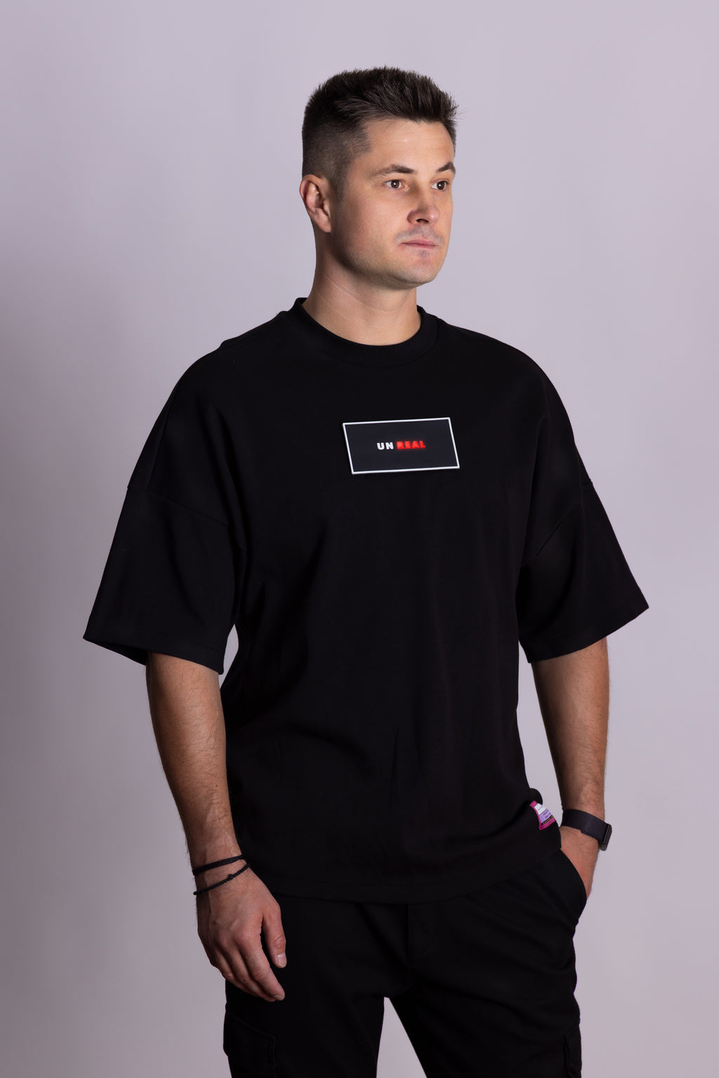 Person, die ein schwarzes Falkenstern-T-Shirt mit Falkenmotiv auf dem Rücken vor einem einfarbigen Hintergrund trägt