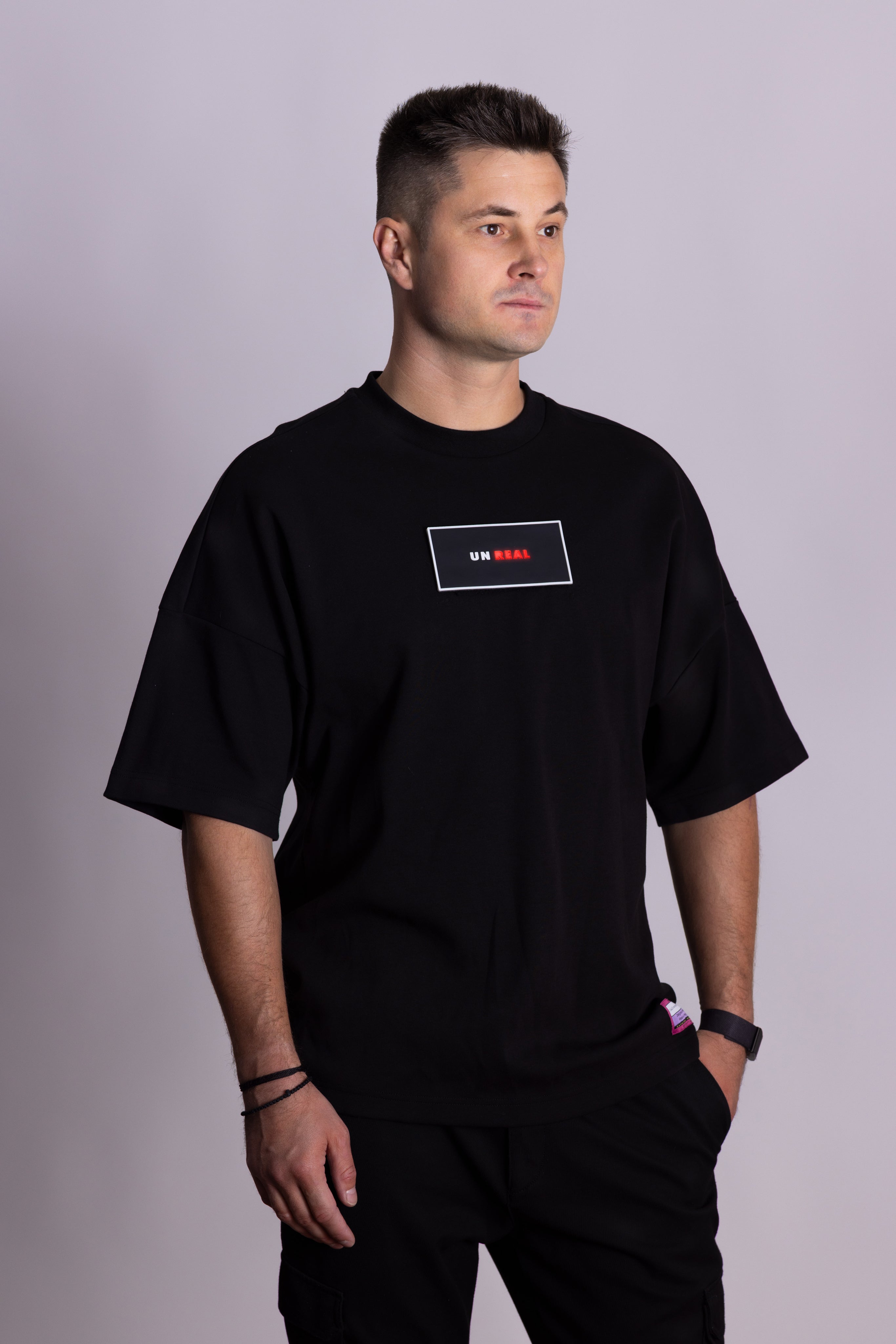 Person, die ein schwarzes Falkenstern-T-Shirt mit Falkenmotiv auf dem Rücken vor einem einfarbigen Hintergrund trägt